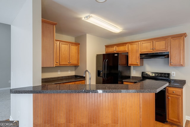 kitchen featuring under cabinet range hood, brown cabinets, a peninsula, and black appliances