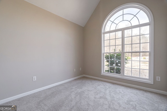 spare room featuring lofted ceiling, baseboards, and carpet flooring