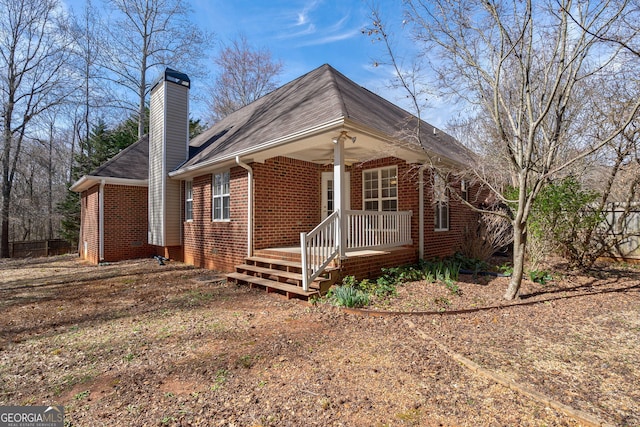 view of front of house featuring ceiling fan, brick siding, and a chimney