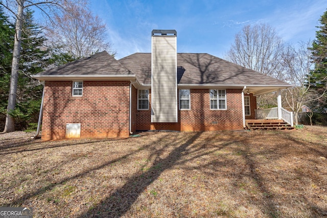 back of property with a yard, a chimney, covered porch, and brick siding