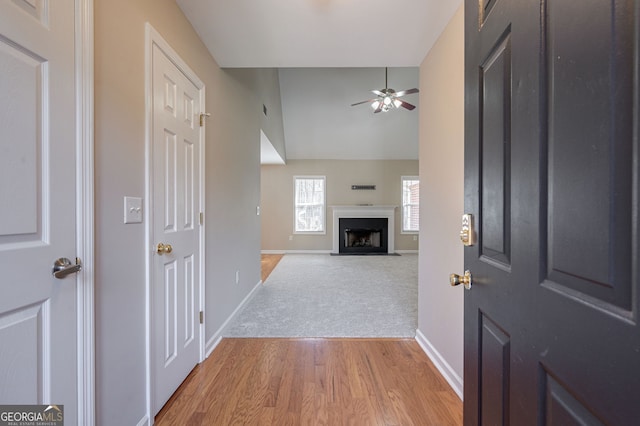 entrance foyer with a fireplace with flush hearth, light wood-style floors, a ceiling fan, light carpet, and baseboards