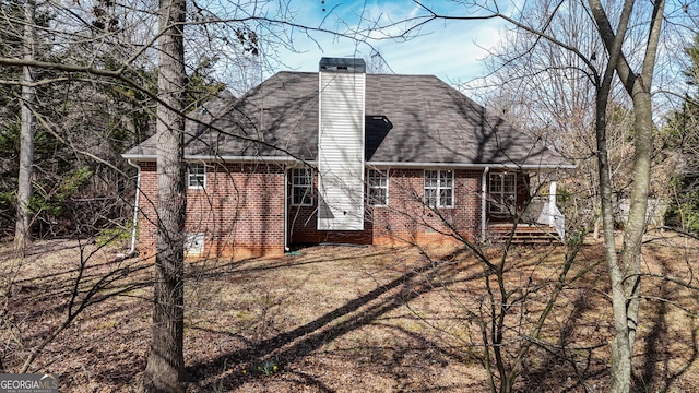 rear view of house with brick siding and a chimney