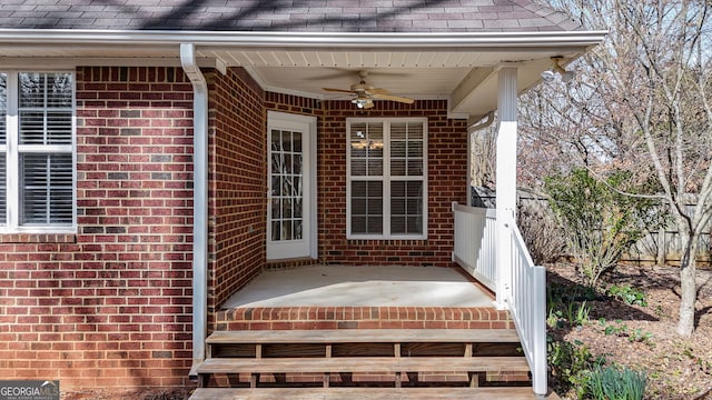 property entrance featuring brick siding, roof with shingles, and a ceiling fan