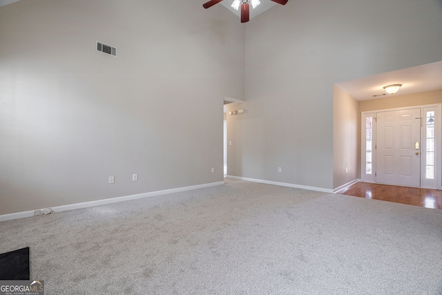 entryway featuring a towering ceiling, baseboards, visible vents, and a ceiling fan