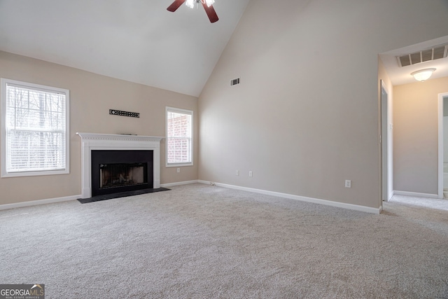 unfurnished living room with light carpet, visible vents, baseboards, a fireplace with flush hearth, and high vaulted ceiling