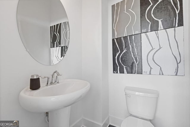 bathroom featuring a sink, toilet, and baseboards