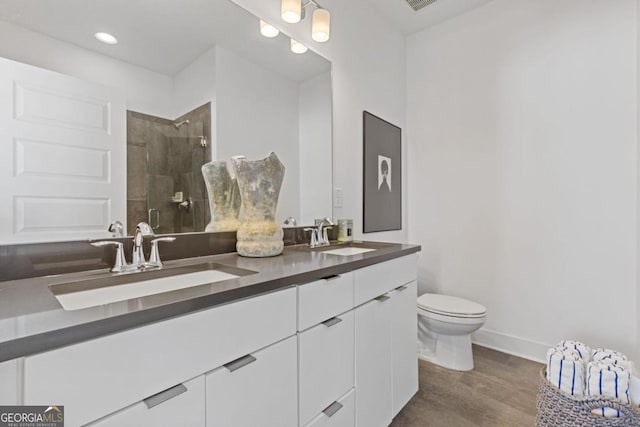 full bathroom with a sink, a tile shower, toilet, and double vanity