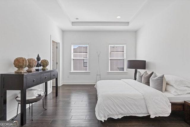 bedroom with a tray ceiling, recessed lighting, dark wood finished floors, and baseboards