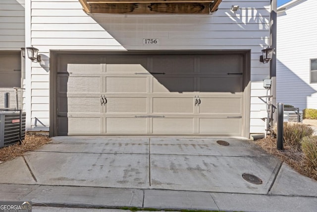 garage with concrete driveway and central AC