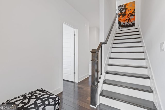 staircase featuring wood finished floors and baseboards