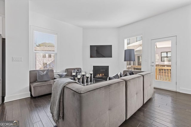 living room featuring baseboards, dark wood-type flooring, and a glass covered fireplace