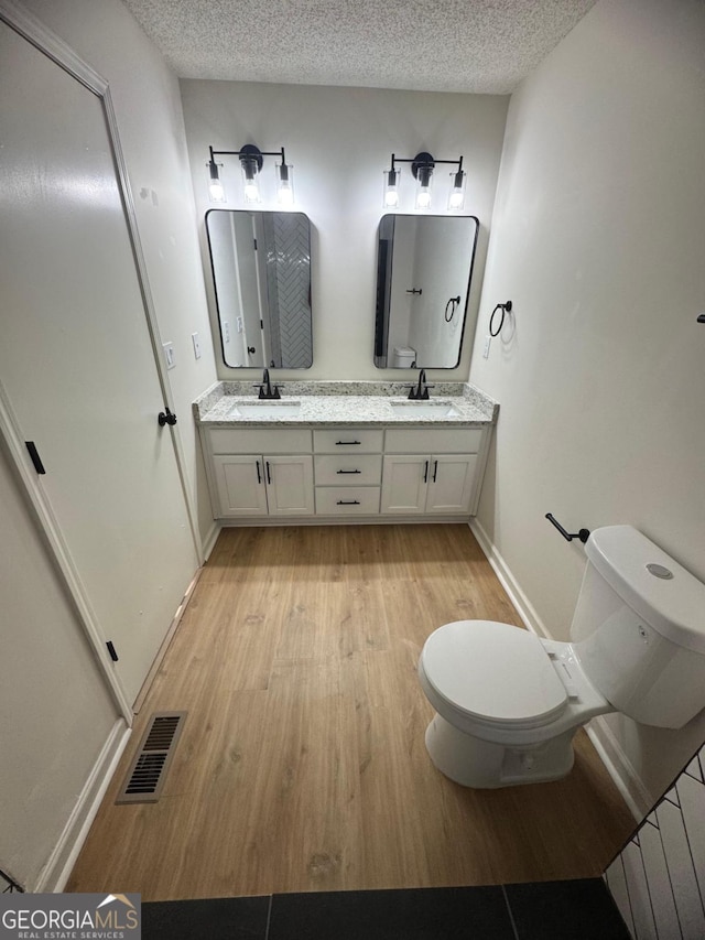 1753 Lee St, Decatur, GA 30035 - bathroom featuring a textured ceiling, toilet, vanity, and wood-type flooring