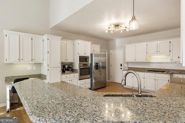 kitchen with stainless steel appliances, a sink, white cabinets, and pendant lighting