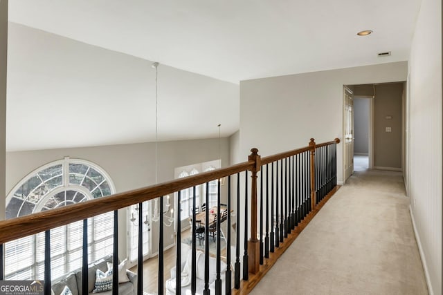 hall featuring lofted ceiling, light colored carpet, and baseboards