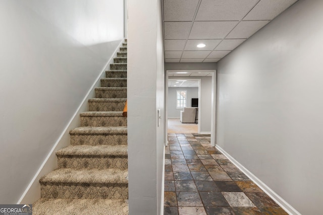 stairs featuring recessed lighting, a drop ceiling, stone tile flooring, and baseboards