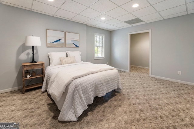 carpeted bedroom featuring a paneled ceiling and baseboards