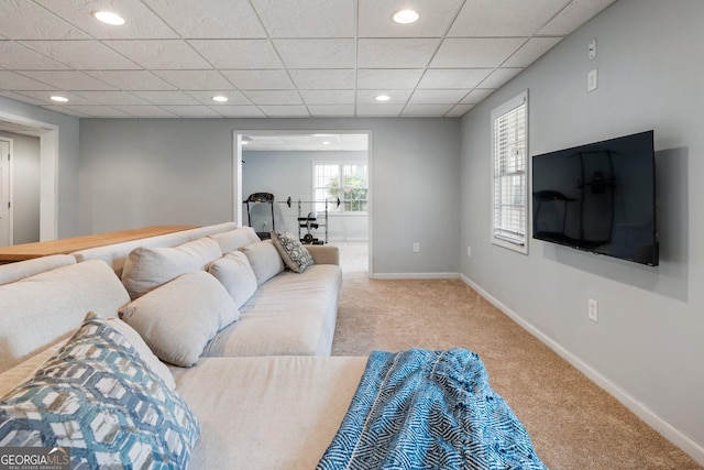 living room featuring recessed lighting, baseboards, a drop ceiling, and light colored carpet