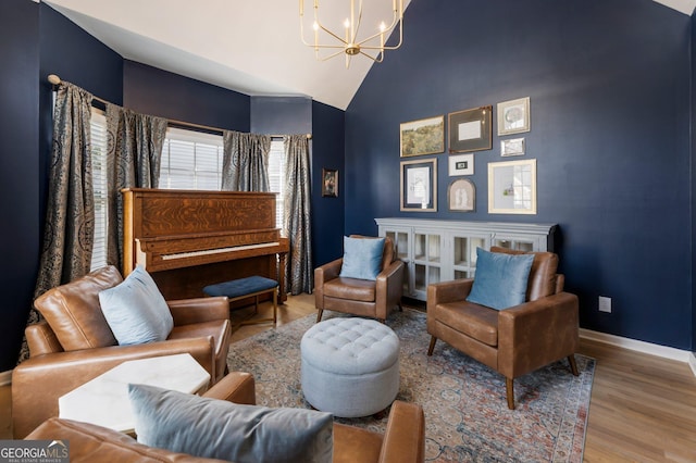 sitting room featuring high vaulted ceiling, a notable chandelier, baseboards, and wood finished floors