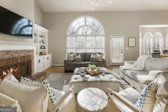 living area featuring a brick fireplace, plenty of natural light, baseboards, and wood finished floors