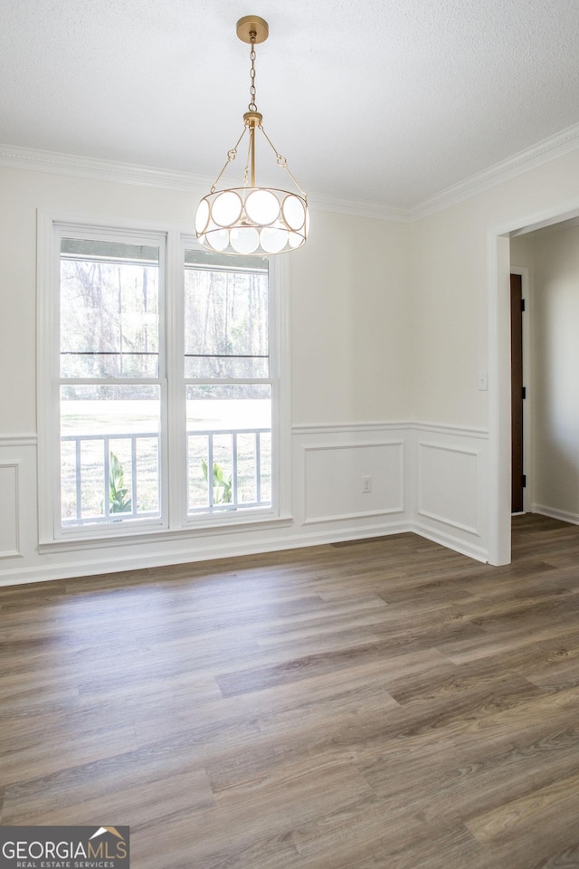 702 Hillmont Dr, Waycross, GA 31503 - unfurnished dining area with ornamental molding, a wainscoted wall, wood finished floors, a chandelier, and a textured ceiling