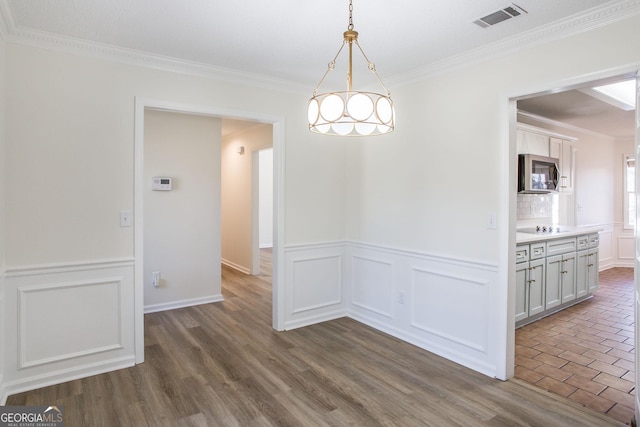 702 Hillmont Dr, Waycross, GA 31503 - unfurnished dining area with ornamental molding, wainscoting, dark wood finished floors, and a decorative wall