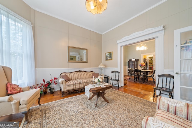 living room featuring crown molding, wood-type flooring, and a notable chandelier