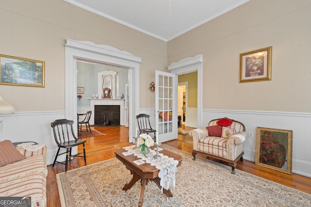 living room featuring a fireplace, ornamental molding, french doors, and wood-type flooring