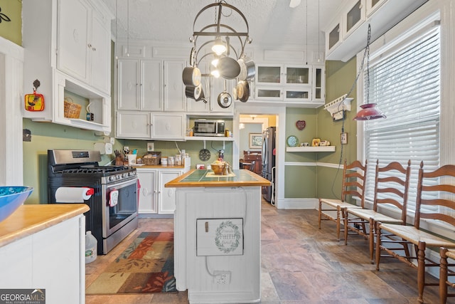 kitchen with decorative light fixtures, stainless steel appliances, a textured ceiling, and white cabinets