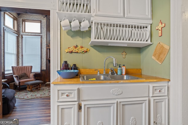 kitchen with sink, white cabinetry, wood-type flooring, and a healthy amount of sunlight