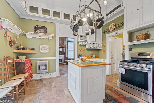 kitchen featuring white cabinetry, a center island, heating unit, stainless steel range with gas stovetop, and a chandelier