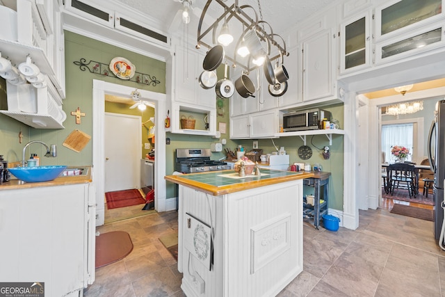 kitchen featuring a chandelier, appliances with stainless steel finishes, sink, pendant lighting, and white cabinetry