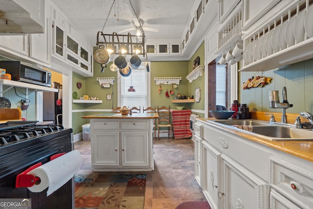 kitchen featuring a textured ceiling, white cabinets, pendant lighting, sink, and a healthy amount of sunlight