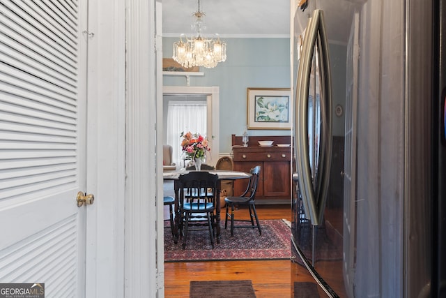 dining space featuring a notable chandelier, ornamental molding, and dark hardwood / wood-style floors