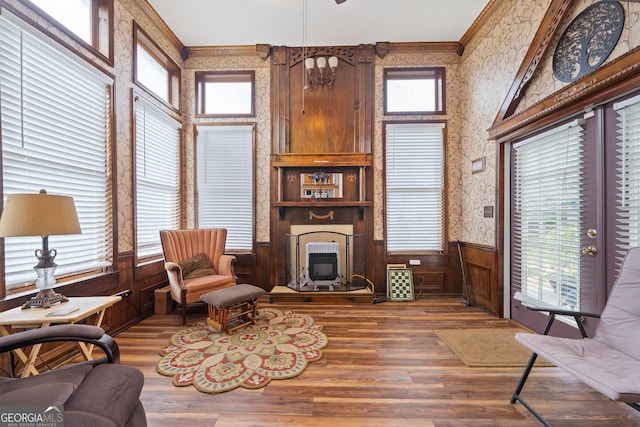 living room featuring plenty of natural light, a large fireplace, crown molding, and wood-type flooring