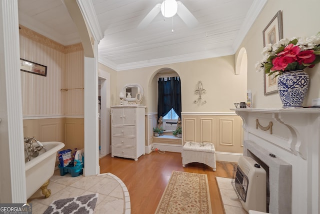 interior space with heating unit, hardwood / wood-style flooring, crown molding, and a bath