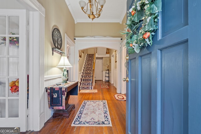 entryway with hardwood / wood-style flooring, crown molding, and an inviting chandelier