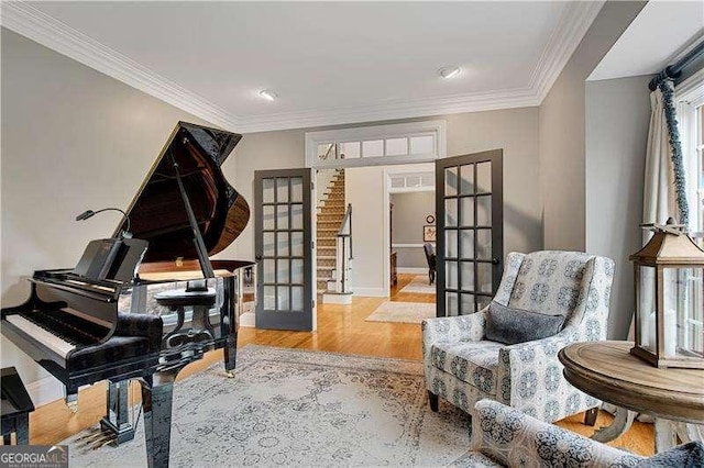 living area with ornamental molding, light wood-type flooring, and french doors