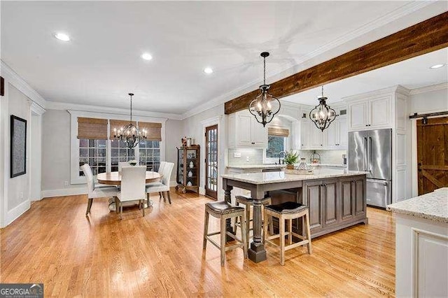 kitchen featuring hanging light fixtures, a chandelier, high quality fridge, a kitchen island, and white cabinetry