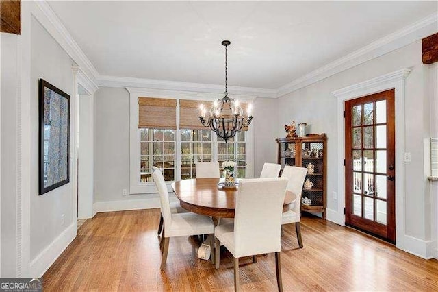 dining area with light wood-type flooring, ornamental molding, and a chandelier