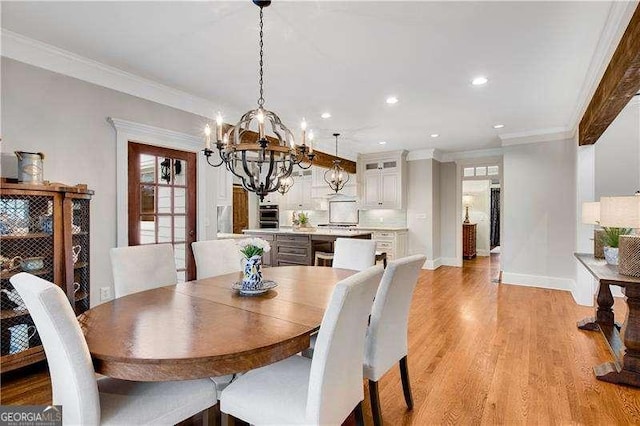 dining area featuring ornamental molding, an inviting chandelier, and light hardwood / wood-style flooring