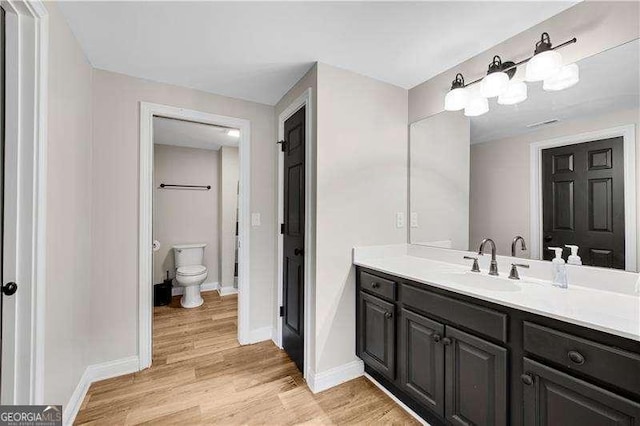 bathroom with wood-type flooring, vanity, and toilet