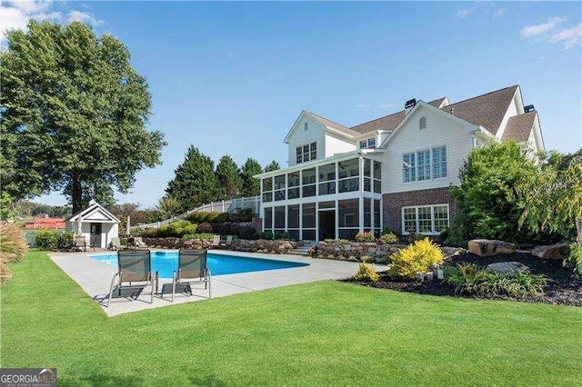 rear view of house featuring a patio, a yard, and a sunroom