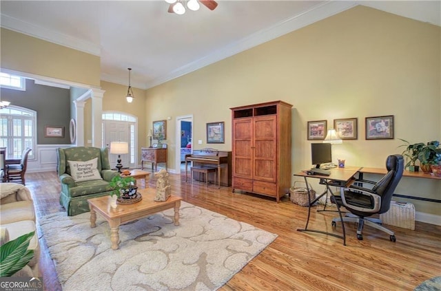 living room featuring light hardwood / wood-style floors, ornamental molding, ornate columns, ceiling fan, and high vaulted ceiling