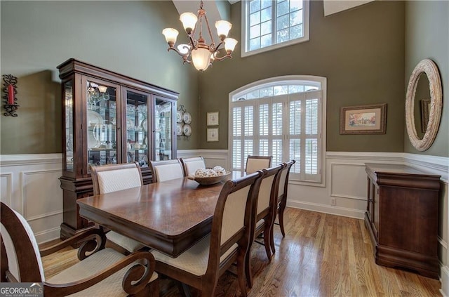 dining area with light hardwood / wood-style floors and an inviting chandelier