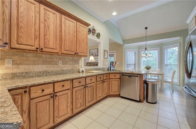 kitchen featuring hanging light fixtures, stainless steel appliances, light stone countertops, sink, and tasteful backsplash