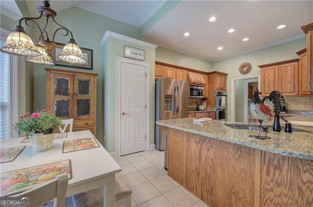 kitchen featuring appliances with stainless steel finishes, light tile patterned floors, light stone counters, pendant lighting, and ornamental molding