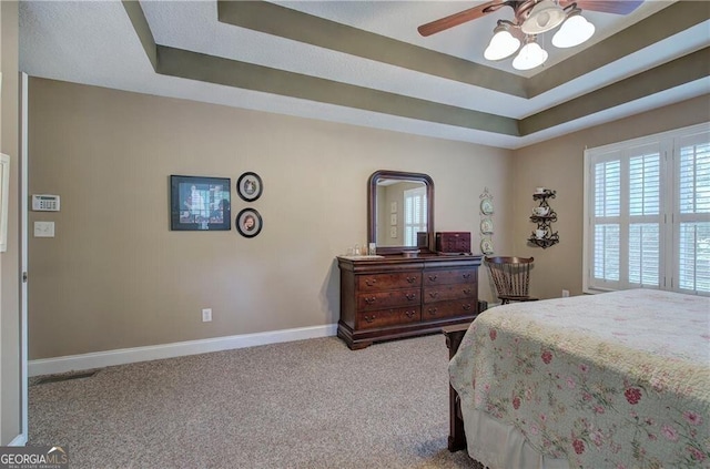 bedroom with a tray ceiling, light carpet, and ceiling fan