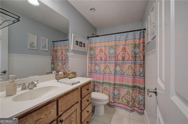 bathroom with curtained shower, vanity, a textured ceiling, tile patterned flooring, and toilet