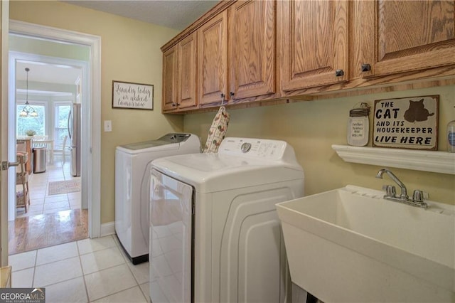 clothes washing area with cabinets, light tile patterned floors, sink, and washing machine and clothes dryer