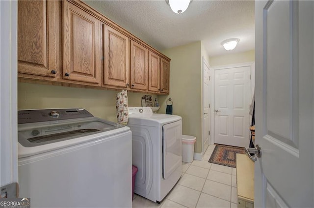 washroom featuring light tile patterned flooring, cabinets, washer and dryer, and a textured ceiling